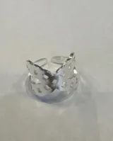 Anillo ancho de acero plateado con diseño calado de perforaciones geométricas.