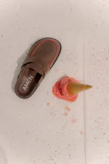 Suecos de cuero vacuno color marrón con detalles de pespuntes en hilo rojo en el empeine, suela plana y diseño destalonado.
