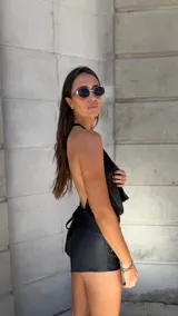 Top negro brillante con escote drapeado y espalda descubierta.