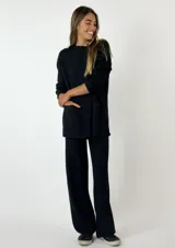 Conjunto negro de tejido acanalado, compuesto por un sweater de mangas largas con cuello redondo y bolsillos frontales, y un pantalón de corte recto.