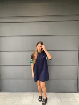 Vestido corto azul marino de hilo, con cuello redondo y mangas cortas con rayas verdes y blancas.