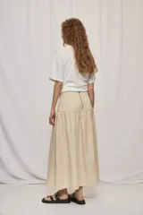 Falda midi de denim color beige, con diseño de volados y caída fluida.