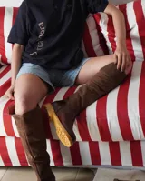 Botas altas de cuero marrón combinadas con gamuza blanca con estampado de vaca, forradas en cuero y con cierre de bronce.