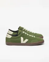 Championes Veja modelo Panenka, confeccionados en gamuza color verde oliva. Presentan el logo lateral en forma de V en color crema, suela de goma marrón y detalle en el talón con el nombre de la marca.