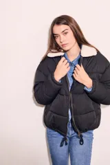 Campera puffer negra con cuello de corderito color crema, cierre frontal con cremallera y cordón ajustable en el ruedo.