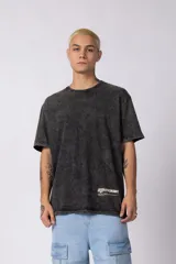 Remera de algodón con efecto desgastado acid wash, corte semi-oversize, cuello redondo y estampa gráfica pequeña en la parte inferior frontal.