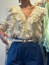 Cinturón marrón de cuero con hebilla plateada rectangular con diseño de flores y apliques metálicos circulares con diseño de flores.