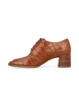 Zapato acordonado tipo oxford con taco cuadrado de madera, confeccionado en cuero con textura de reptil en color suela.