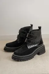Borcegos de caña baja combinados en gamuza negra y cuero con textura de reptil. Presentan cierre mediante tiras de velcro en el empeine, suela track robusta con costuras visibles y taco cuadrado.