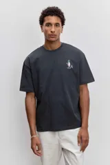 Remera de algodón color gris oscuro, de corte holgado y manga corta, con un pequeño estampado gráfico en el pecho.