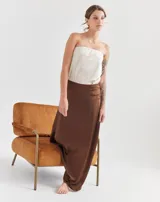 Top strapless de color beige, con diseño liso y ajuste al cuerpo. Cuenta con forro interno con elástico en el busto para mayor sujeción y pequeños tajos laterales en el ruedo.