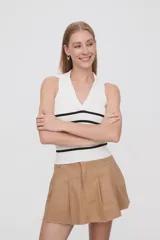 Top blanco de tejido de punto acanalado, sin mangas, con cuello polo y rayas horizontales negras.