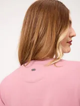 Remera blanca de manga corta con vuelta en los puños y detalle de botón dorado. Presenta cuello redondo y corte recto.
