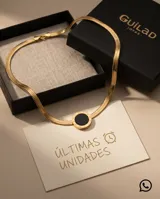 Collar tipo gargantilla de acero con baño de oro, compuesto por una cadena de eslabones planos tipo serpiente y un dije circular central con piedra ónix negra y números romanos grabados en el borde.