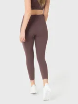 Calza deportiva de tiro alto con largo al tobillo, confeccionada en tejido elástico color marrón. Presenta costuras reforzadas, pretina ancha para mayor ajuste y bolsillos laterales integrados.