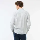 Camisa de manga larga confeccionada en mezcla de lino y algodón, con diseño de rayas verticales en tonos verde y blanco, cuello abotonado y cierre frontal de botones.