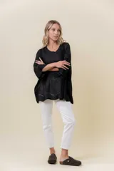 Buzo de tejido liviano con brillo sutil tipo lurex, color beige o dorado claro. Presenta un calce suelto (oversize) con mangas amplias y cuello redondo. El ruedo tiene un detalle de terminación festoneado con pequeños calados.