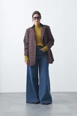 Blazer de corte relajado con estampado de cuadros tipo pied de poule en tonos rojizos y verdes. Presenta solapas clásicas en color azul oscuro y estructura definida.