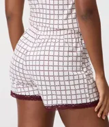 Short de pijama femenino confeccionado en tejido peach touch de poliéster, con cintura elastizada, botones frontales y encaje bordó en los bajos. Presenta un estampado geométrico con pequeños corazones en tonos blancos y oscuros.