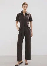 Enterito largo de algodón estilo tejano, color marrón, con cuello camisero, mangas cortas, cierre frontal con cremallera y cinturón ajustable en la cintura.