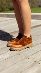 Bota corta color marrón óxido de cuero gamuzado, con plataforma de goma color beige y cierre frontal con cremallera.