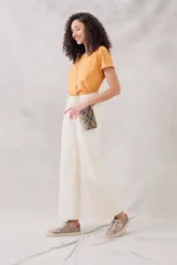 Remera negra de algodón peinado, ajustada al cuerpo, con cuello redondo y detalles de vainillas caladas en el escote y los hombros. Las mangas son cortas y están dobladas hacia afuera.