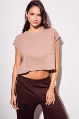 Remera gris de algodón con poliéster, corte crop, mangas cortas y bolsillo en el pecho.