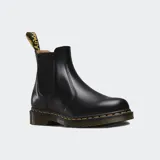 Botas Chelsea Dr. Martens modelo 2976, confeccionadas en cuero liso negro con acabado brillante. Presentan paneles elásticos laterales, tirador en el talón y la característica suela con amortiguación de aire y costuras amarillas visibles.