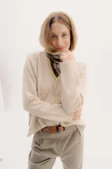 Polera tejida en lambswool color beige, con cuello alto y diseño de intarsia exclusivo de la colección. Presenta botones forrados que permiten modular la apertura del cuello.