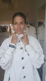 Tapado blanco de diseño holgado con cuello alto envolvente, cierre frontal con botones y mangas largas con detalles en puños.