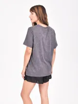 Remera de manga corta, corte holgado y efecto gastado (acid wash) en color gris oscuro. Estampado frontal con una rosa roja, estrellas y el texto "ROCK & ROLL" y "make some noise".