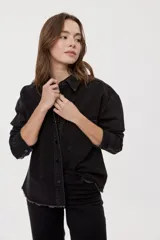 Sobrecamisa de denim negro con calce relajado, mangas largas, cuello clásico, cierre frontal con botones y bolsillo aplicado. Cuenta con detalles de strass en toda la prenda y terminación desflecada en el bajo.