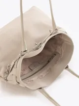 Bolso tipo tote color gris, confeccionado en cuero vacuno, con asas largas para hombro, detalles metálicos personalizados, cierre central y llavero con candado y llave colgante.