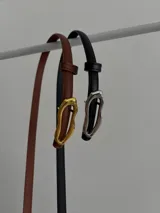 Cinturón fino de ecocuero, con hebilla ovalada irregular metálica.