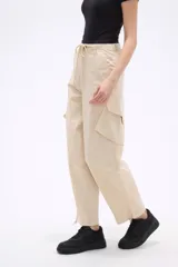 Pantalon cargo de tiro bajo en color beige, con bolsillos laterales amplios y cintura ajustable con cordón.