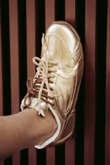 Zapatillas urbanas de cuero color tostado, con cordones verdes y suela de goma.