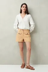 Short de algodón de tiro alto, color beige, con bolsillos delanteros tipo parche con solapa y botones a la vista.