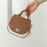 Cartera marrón con solapa color crema, asa corta y correa larga desmontable.