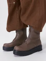 Botas de cuero color marrón topo, de caña corta con cierre metálico frontal y plataforma gruesa de goma negra con suela track.