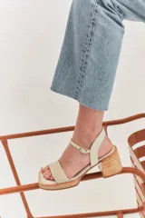 Sandalias de taco cuadrado medio, con base y talón en gamuza color tostado. Presenta una tira frontal de múltiples bandas doradas y una pulsera al tobillo con hebilla metálica.