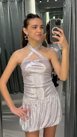 Vestido corto de lurex plateado brillante, con escote halter cruzado, fruncidos en los laterales y falda con volumen tipo globo.