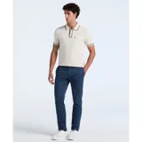 Polo color crema de algodón piqué, con cuello tipo camisa y cierre de botones. Tiene mangas cortas con ribete negro, bolsillo de parche en el pecho y logo bordado de pingüino.