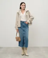 Chaqueta color beige de napa y piel sintética con cuello con cierre de hebilla y almeja, mangas largas con hombros caídos, tirantes en los puños, cierre de cremallera oculta, bolsillos laterales, cierre de hebilla y almeja en el dobladillo y placa en T ovalada en la parte posterior.