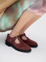 Guillerminas estilo Mary Jane de cuero gamuza color bordó, con detalle de pespuntes en hilo blanco, tira en T con hebilla metálica ajustable, taco y plataforma plana de goma negra.