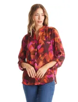 Blusa de gasa con estampado abstracto en tonos marrones, naranjas y fucsias. Presenta cuello mao con escote en V y mangas largas con sistema de ajuste mediante presilla y botón.