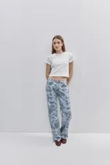 Jean de tiro medio con calce amplio y piernas wide leg, confeccionado en denim celeste con estampado floral. Cuenta con diseño de cinco bolsillos y cierre frontal con botón y cremallera.