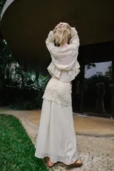 Falda midi de color crudo, con diseño combinado que presenta una parte superior de crochet con motivos florales y una parte inferior de tela fluida con textura arrugada. Incluye forro interior y cierre lateral con cremallera oculta.
