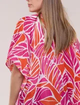 Kimono de gasa ligera color fucsia y naranja, con estampado de hojas, mangas cortas amplias, diseño abierto al frente y detalle de borlas en el ruedo asimétrico.
