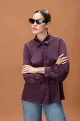 Camisa de seda color violeta oscuro, con cuello clásico, cierre frontal de botones y mangas largas con puños abotonados.