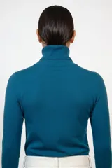 Polera de cuello alto en color azul, de manga larga con puños ajustados y tejido de punto fino.